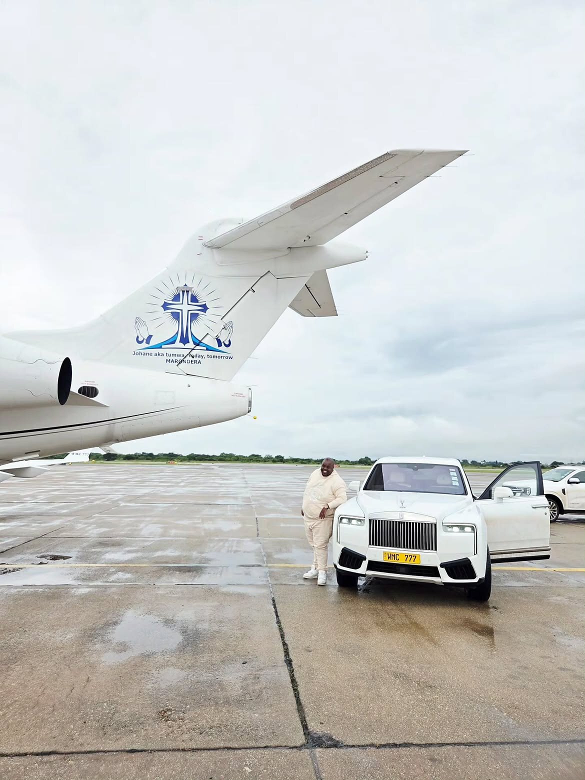 Wicknell Chivayo beside a white Rolls-Royce Cullinan and a private jet on an airport apron